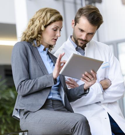 Businesswoman with tablet and doctor talking in hospital