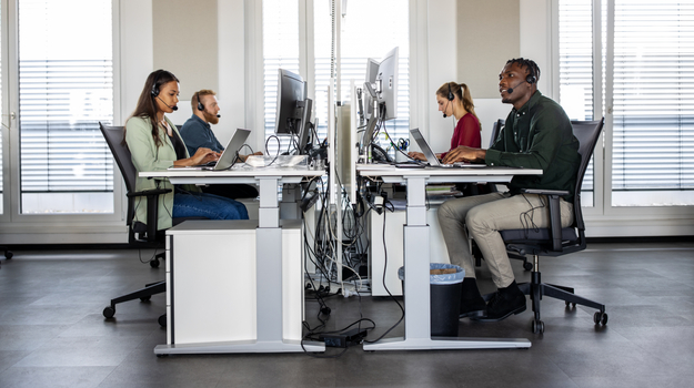 Group of help desk operators wearing headsets and working at their computers in a call center