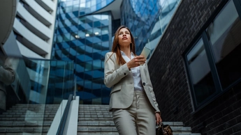 Businesswoman standing in front of her workspace and using phone