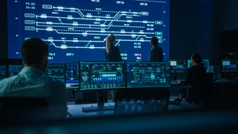 Project Manager and Computer Science Engineer Talking while Using Big Screen Display Showing Infrastructure Infographics and Data