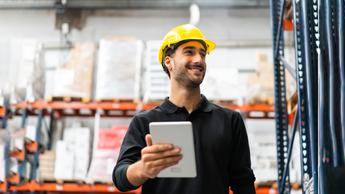 man wearing hard hat smiling in warehouse