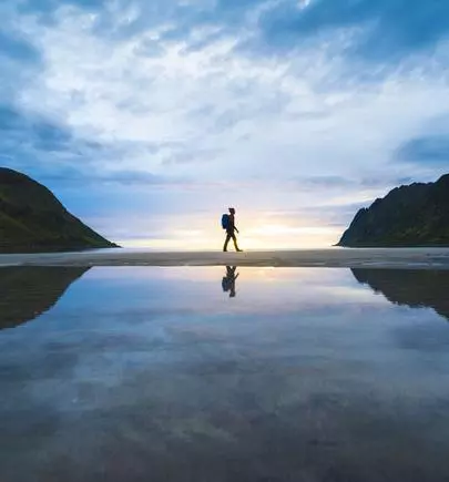 Person walking on the beach at sunset