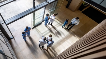 Doctors and patients talking at a busy entrance hall at a hospital - healthcare and medicine concepts