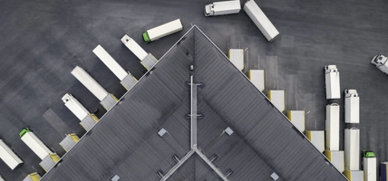 Aerial view of a large distribution warehouse with loading docks and many trucks.