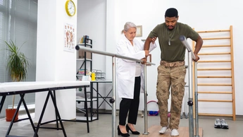 A female doctor assisting a man in walking