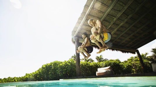 two men jumping into pool