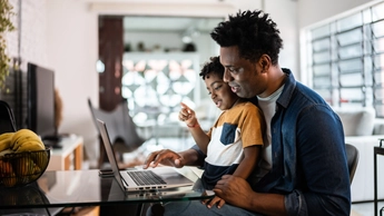 Father using the laptop with son at home