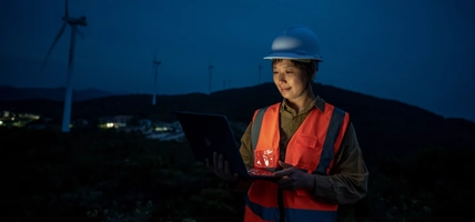 At night, an Asian female engineer works in a wind power station