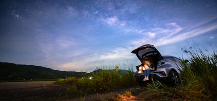 woman sitting in trunk of car with dusk sky above