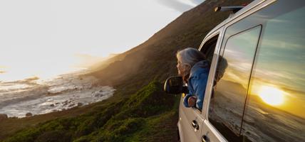 person with head out of car window admiring the view