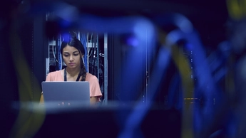 Female technician using laptop in server room