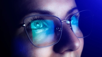 The girl is wearing glasses and looking upwards