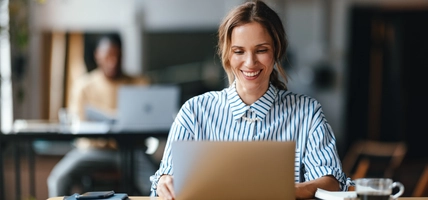 she is reading something on his laptop while sitting at her office desk