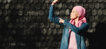 Woman with cancer showing strength with arms outdoors