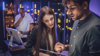 Engineers examining data on digital tablet together in server room
