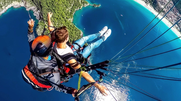 Two people skydiving over water and cliffs