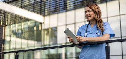 Healthcare employee holding tablet over railing