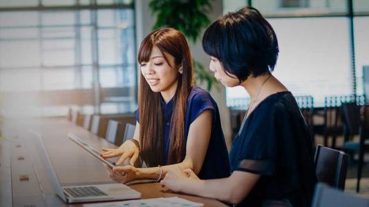 two women working together at a counter with laptop