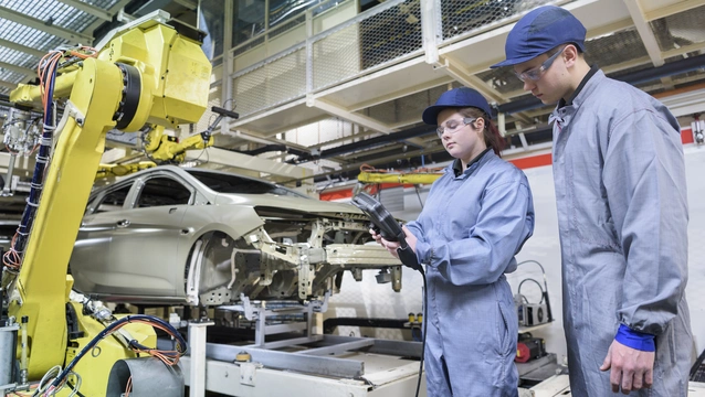 apprentice engineers with car sealant robot in car