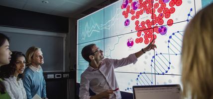 Man pointing to DNA strands on a screen