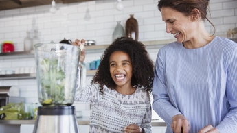 young girl making healthy smoothie happily