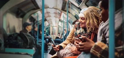 people sitting on public transportation looking at mobile device