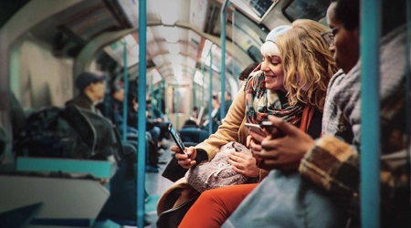 people sitting on public transportation looking at mobile device