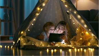 mother and daughter watching tablet in lit up tent