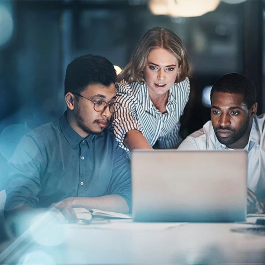 Cropped shot of three young businessmpeople working together on a laptop in their office late at night