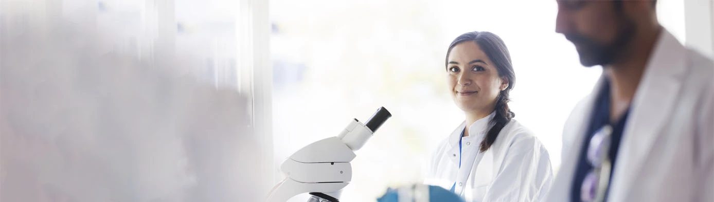 Two scientist working together in laboratory, using microscopes 