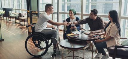 man in wheelchair sitting with colleagues