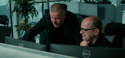 two men looking at screen together in office setting