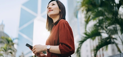 Women is using phone and seeing building.