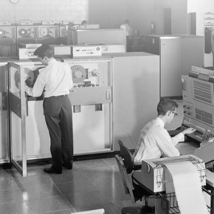 black and white image of two men working on old machines