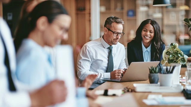 Two smiling diverse businesspeople using a laptop together