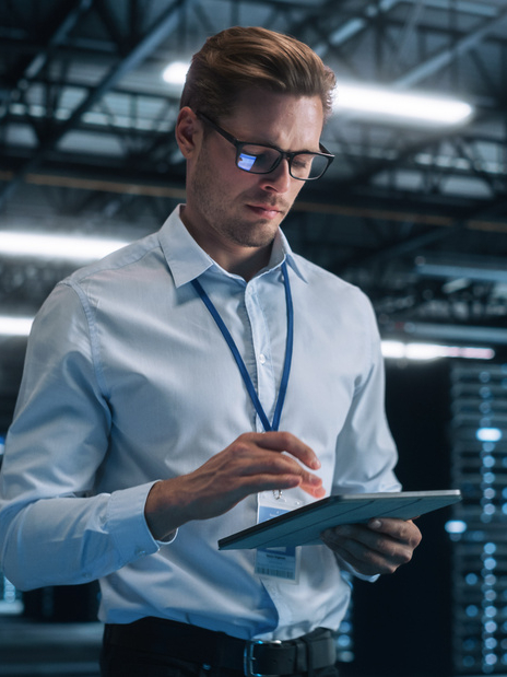 Late at Night in Private Office Businessman Looking Away while Works on a Laptop. Succesful Businessman and e-Business Entrepreneur Overlooking Server Farm Cloud Computing Facility