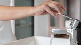 Woman's hand turning a faucet handle to turn on water