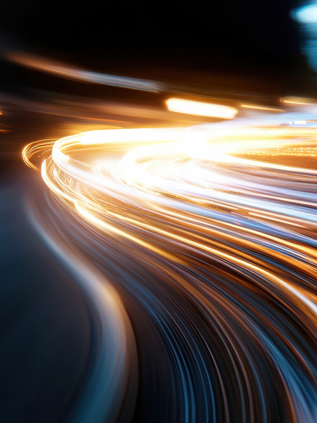 Dynamic streaks of light illuminate the urban nightscape, capturing the energy and movement of a bustling city as vehicles pass by, creating vibrant visual excitement.