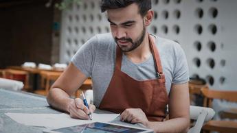 A man is writing something at his workplace