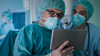 Two medical experts using palmtop in operating room