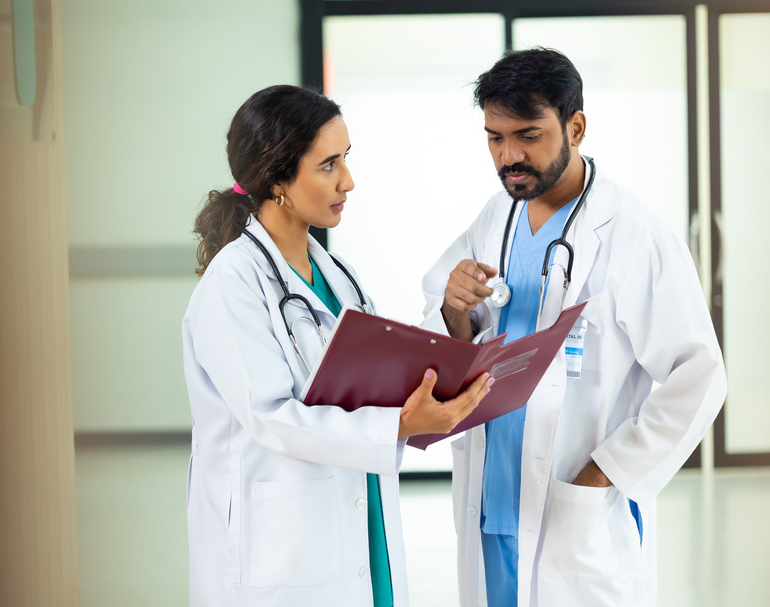 teamwork concept : Two professional doctors meeting discussing diagnosis, checking test results in clinic. Medical staff, healthcare. Diverse people Indian and hispanic latin doctor