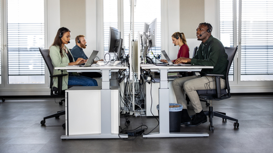 Group of help desk operators wearing headsets and working at their computers in a call center