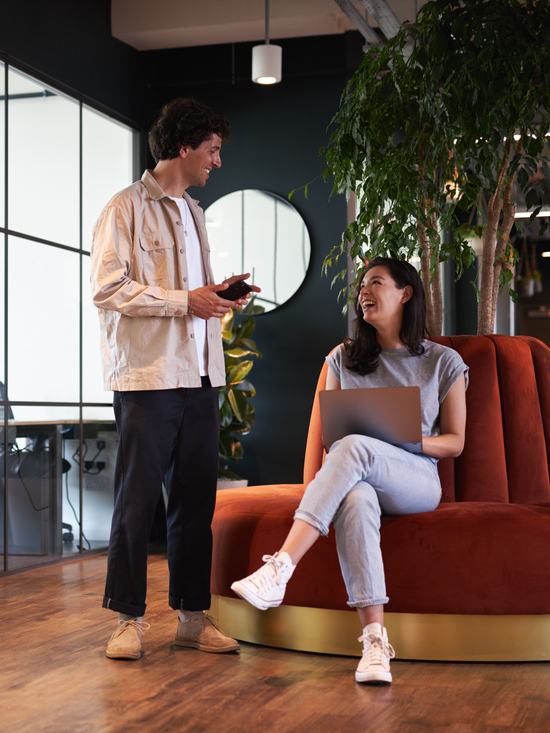 Young couple in work space for start up business have meeting in seating area of open plan office