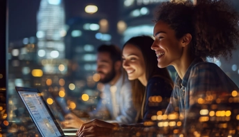 Three people are sitting at a table with a laptop open in front of them 
