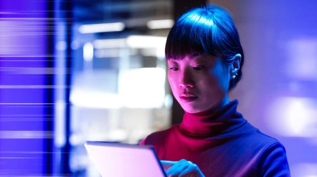 woman looking at tablet surrounded by blue lights