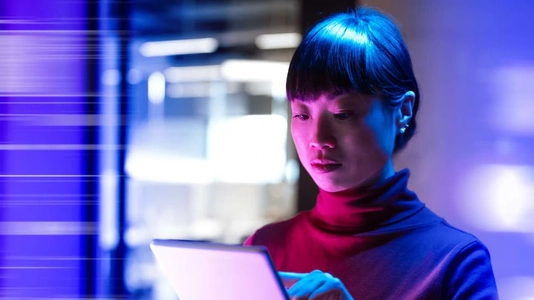 woman looking at tablet surrounded by blue lights