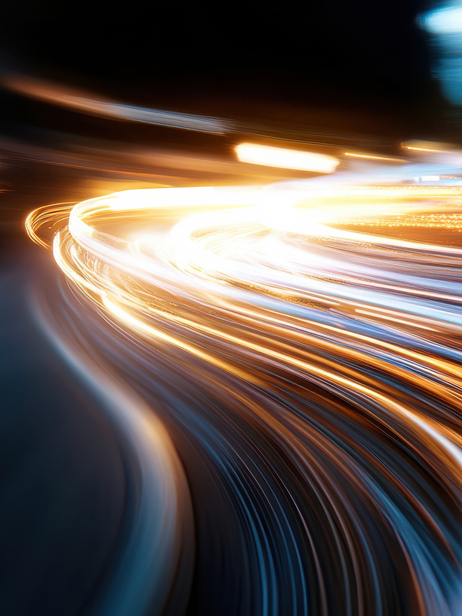Dynamic streaks of light illuminate the urban nightscape, capturing the energy and movement of a bustling city as vehicles pass by, creating vibrant visual excitement.