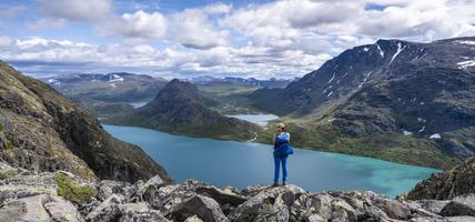 person standing at edge of mountain terrain overlooking more mountains and water