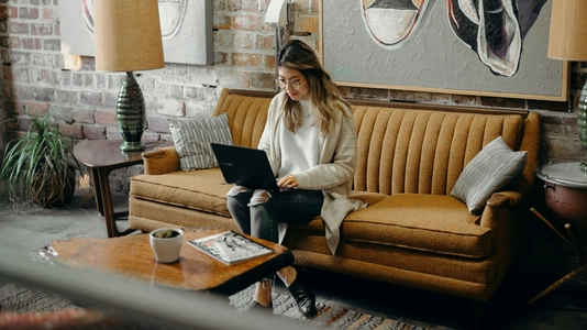 woman sitting on yellow couch with laptop