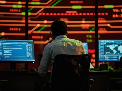 man wearing headset working in room of screens